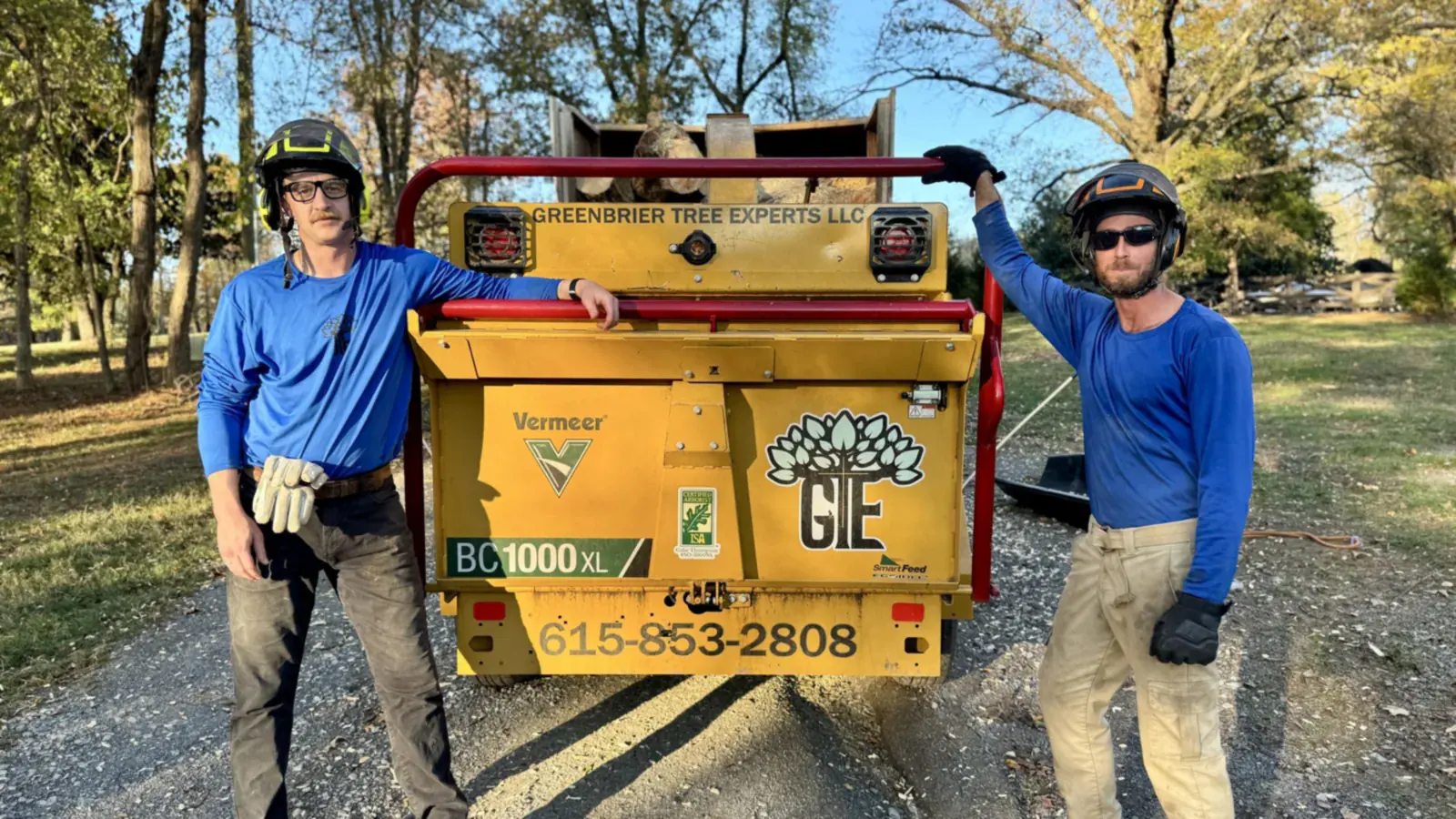Two Greenbrier Tree Experts crew members standing with the chipper after a job