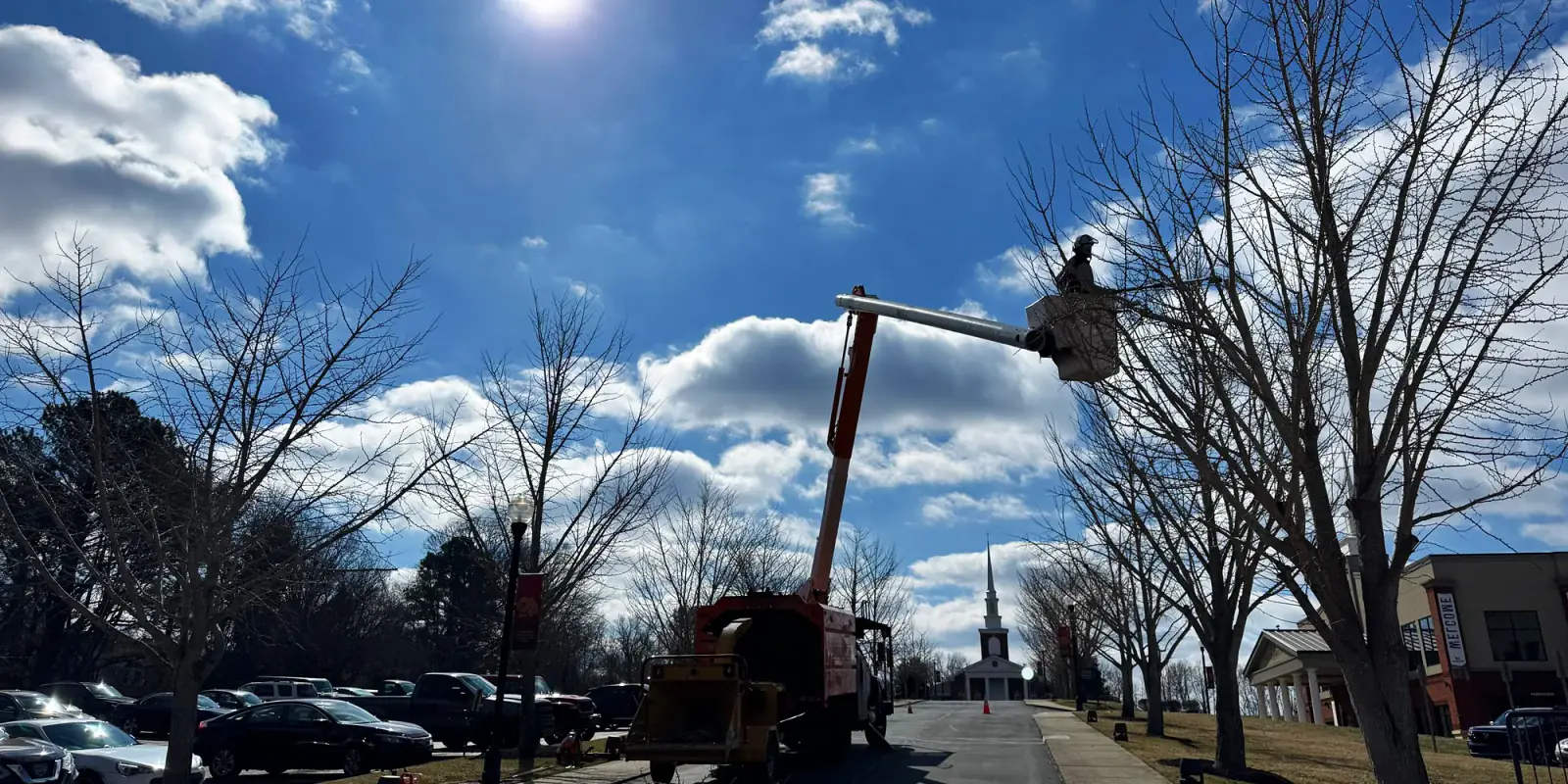 Greenbrier Tree Experts bucket operator working high over a Greenbrier street, chip truck below