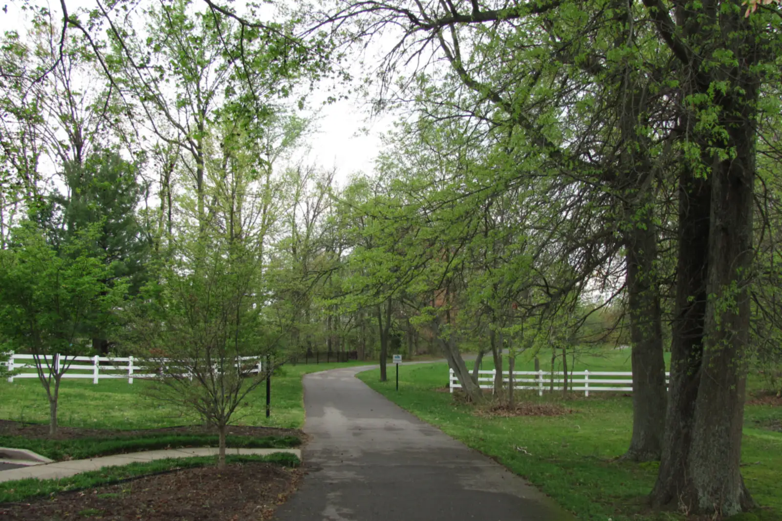 The White House Greenway path running through mature hardwoods beside a white board fence in White House, Tennessee